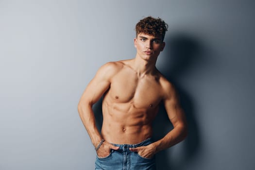 man bicep body lifestyle shirtless sexy muscular jeans studio gray background muscle athletic handsome standing model chest bodybuilder