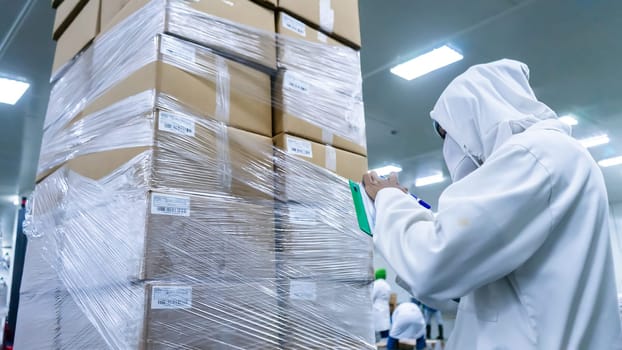 Latino safety and quality inspector inventorying product packed in cardboard boxes at a food processing plant
