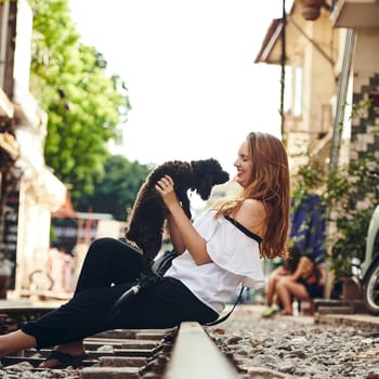 Make friends wherever you go. a young woman playing with a dog while exploring a foreign city