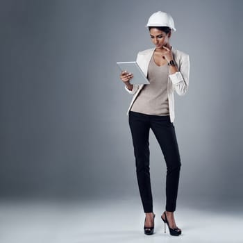 This tablet makes my job so much simpler. a well-dressed civil engineer using her tablet while standing in the studio