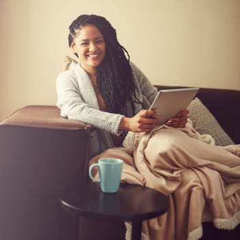 Make your day off count. a young woman using her tablet while relaxing at home