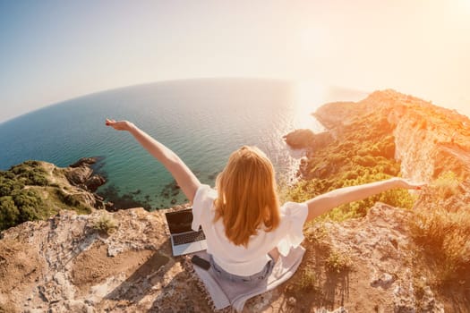 Woman sea laptop. Business woman in yellow hat working on laptop by sea. Close up on hands of pretty lady typing on computer outdoors summer day. Freelance, digital nomad, travel and holidays concept.