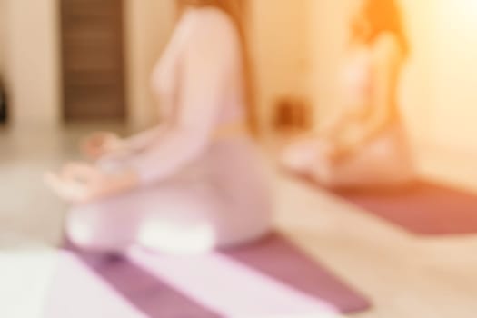 Young woman with long hair in white swimsuit and boho style braclets practicing outdoors on yoga mat by the sea on a sunset. Women's yoga fitness routine. Healthy lifestyle, harmony and meditation