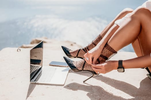 Happy girl doing yoga with laptop working at the beach. beautiful and calm business woman sitting with a laptop in a summer cafe in the lotus position meditating and relaxing. freelance girl remote work beach paradise