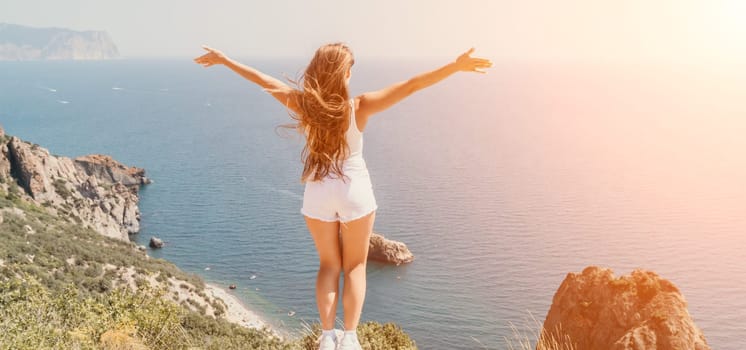 Woman travel sea. Young Happy woman in a long red dress posing on a beach near the sea on background of volcanic rocks, like in Iceland, sharing travel adventure journey