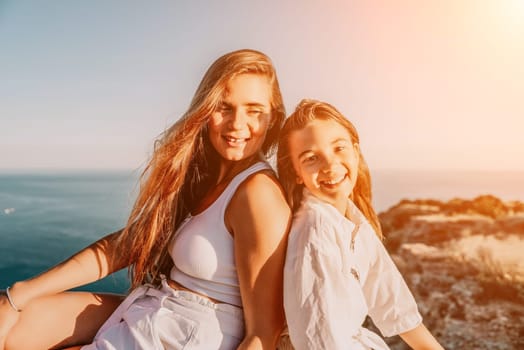 Close up portrait of mom and her teenage daughter hugging and smiling together over sunset sea view. Beautiful woman relaxing with her child.