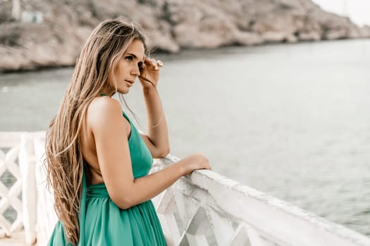 Woman sea trevel green dress. Side view a happy woman with long hair in a long mint dress posing on a beach with calm sea bokeh lights on sunny day. Girl on the nature on blue sky background