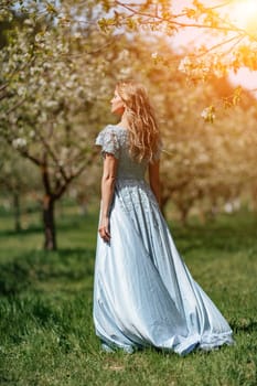 Portrait of a blonde in the park. Happy woman with long blond hair in a blue dress