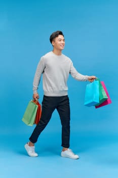 Full length photo of glad nice looking man stylish clothes go mall empty space hold carry purchases