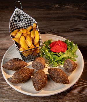 Traditional kebbe and pita bread on big round plate in lebanese restaurant. High quality photo