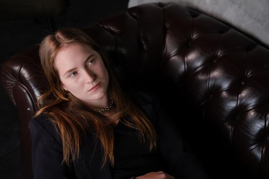 portrait of confident woman in black in dark room. pensive serious people. business woman. feminine. millennial people.