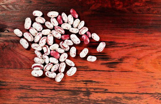 Fresh borlotti beans on red wooden table, beans with red specks on creamy white background , common beans or pinto beans