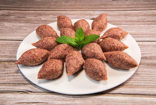 Traditional kebbe and pita bread on big round plate in lebanese restaurant. High quality photo