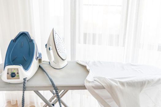 Steam generator iron standing on ironing board near panoramic window