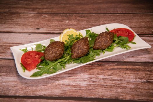 Traditional kebbe and pita bread on big round plate in lebanese restaurant. High quality photo