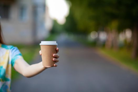 White paper cup with coffee in woman hand. Time for drink coffee in city. Coffee to go. Enjoy moment, take a break. Disposable paper cup closeup. Delicious hot beverage. Blank space for text, mockup