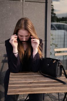 pretty brunette woman sitting by wooden table outside. feminine. millennial people. lady on coffee break.