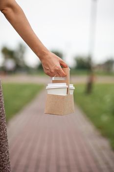 White paper cup with coffee in woman hand. Time for drink coffee in city. Coffee to go. Enjoy moment, take a break. Disposable paper cup closeup. Delicious hot beverage. Blank space for text, mockup