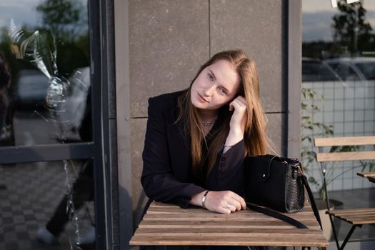 pretty brunette woman sitting by wooden table outside. feminine. millennial people. lady on coffee break.