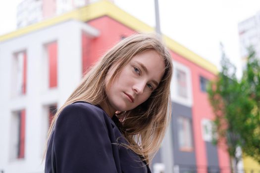 portrait of confident attractive brunette woman in black on background of colorful bright buildings. business woman. feminine. millennial people.