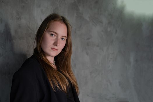 portrait of confident serious brunette woman in black clothes on dark background. femininity.