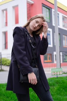 portrait of confident attractive brunette woman in black on background of colorful bright buildings. business woman. feminine. millennial people.