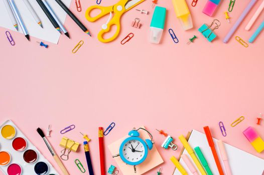 Creative student desk with school supplies and copy space in center. Top view or flat lay. Trendy back to school flat lay on pink background