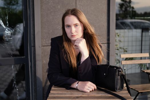 pretty brunette woman sitting by wooden table outside. feminine. millennial people. lady on coffee break.