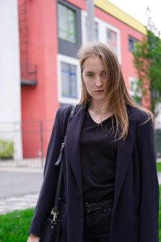 portrait of confident attractive brunette woman in black on background of colorful bright buildings. business woman. feminine. millennial people.