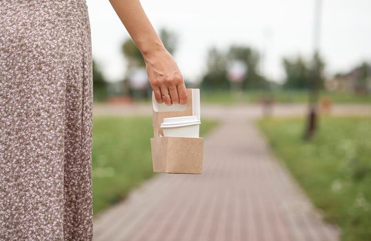 White paper cup with coffee in woman hand. Time for drink coffee in city. Coffee to go. Enjoy moment, take a break. Disposable paper cup closeup. Delicious hot beverage. Blank space for text, mockup