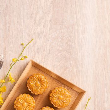 Moon cakes with tea on bright wooden table, holiday concept of Mid-Autumn festival traditional food layout design, top view, flat lay, copy space.