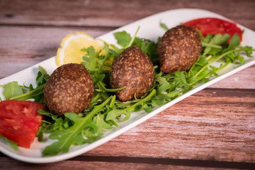 Traditional kebbe and pita bread on big round plate in lebanese restaurant. High quality photo