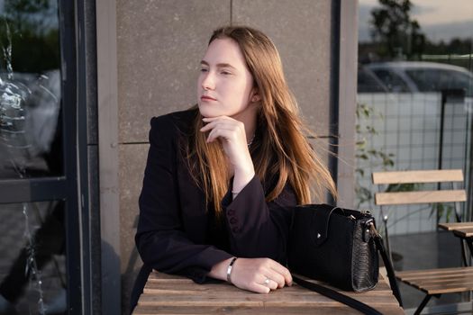 pretty brunette woman sitting by wooden table outside. feminine. millennial people. lady on coffee break.