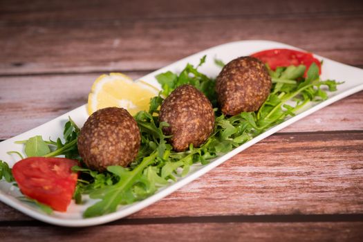 Traditional kebbe and pita bread on big round plate in lebanese restaurant. High quality photo