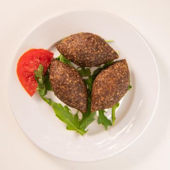 Traditional kebbe and pita bread on big round plate in lebanese restaurant. High quality photo