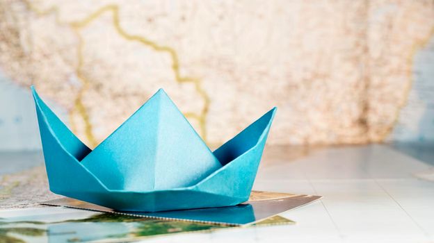 Beautiful blue paper boat on postcard and world map ,