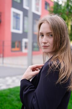 portrait of confident attractive brunette woman in black on background of colorful bright buildings. business woman. feminine. millennial people.