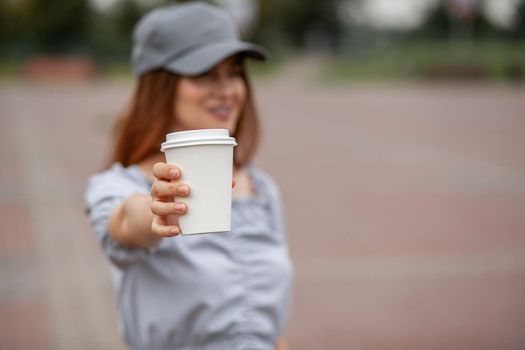 White paper cup with coffee in woman hand. Time for drink coffee in city. Coffee to go. Enjoy moment, take a break. Disposable paper cup closeup. Delicious hot beverage. Blank space for text, mockup