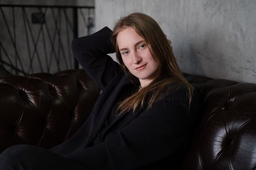 portrait of confident serious brunette woman in black clothes on dark background. femininity.