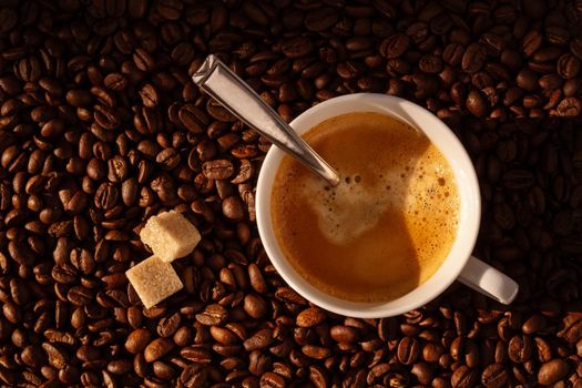 White coffee cup and coffee beans around, top view