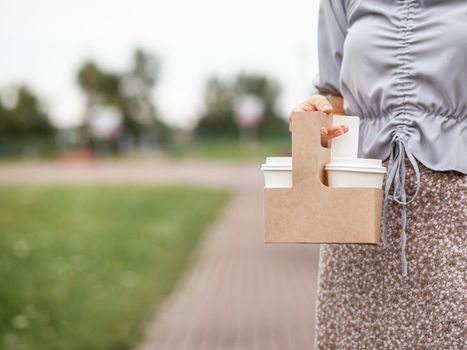 Two white paper cup with coffee in woman hand. Time for drink coffee in city. Coffee to go. Enjoy moment, take a break. Disposable paper cup closeup. Delicious hot beverage. Blank space for text,