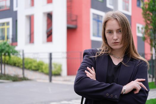 portrait of confident attractive brunette woman in black on background of colorful bright buildings. business woman. feminine. millennial people.