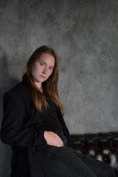 portrait of beautiful confident brunette woman in black in grey dark room. business woman. feminine. millennial people. stylish fashion clothes.