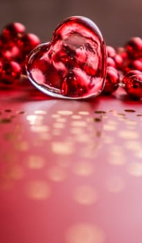 Shining transparent heart and red beads. Perfect Valentine's Day greeting card background. Vertical image in red tone