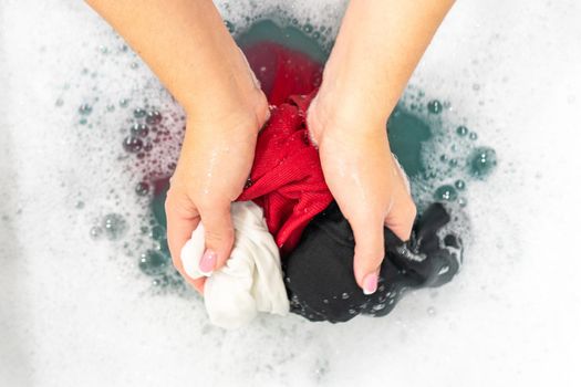 Female hands washing color clothes in basin