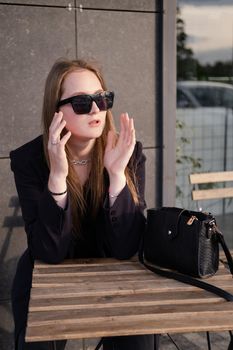 pretty brunette woman sitting by wooden table outside. feminine. millennial people. lady on coffee break.