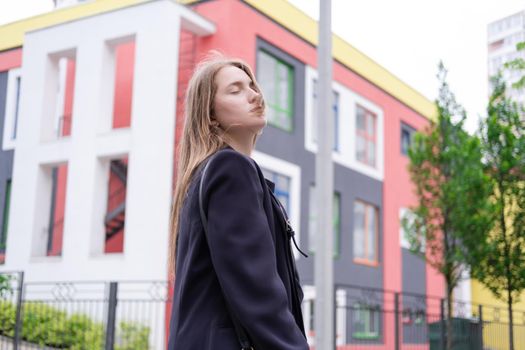 pretty brunette woman on background of bright modern buildings. feminine. millennial people. lady on walk.