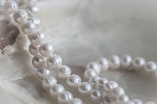 Nature white string of pearls on marble background in soft focus, with highlights.