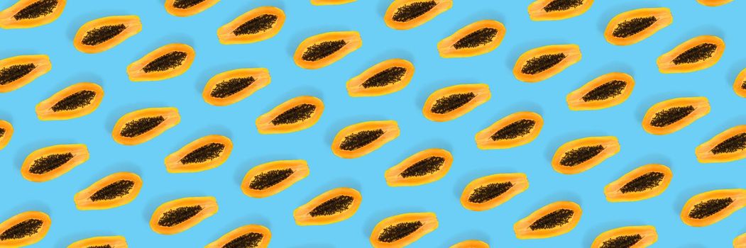 Fresh ripe papaya background on blue backdrop. Modern tropical abstract background. Top view. Creative design, minimal flat lay concept. Trend tropical fruit food background - not seamless pattern