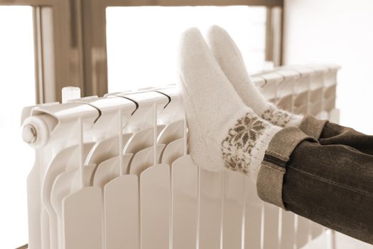 Woman warming up with feet on heater